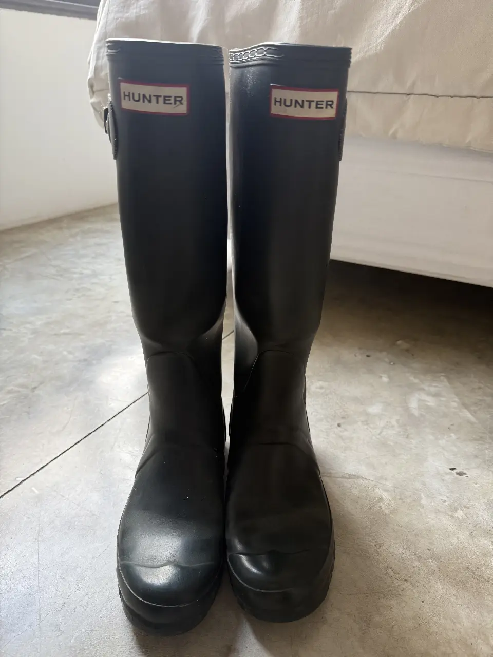Botas de lluvia Hunter azul oscuras parecen negras, ideales para días lluviosos. Tienen el logo de la marca en la parte superior. Perfectas para un look casual y funcional.