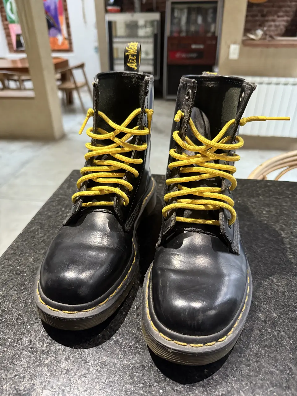 Borcegos Dr. Martens negros con cordones amarillos. Un clásico del calzado, ideales para un look rocker o casual.