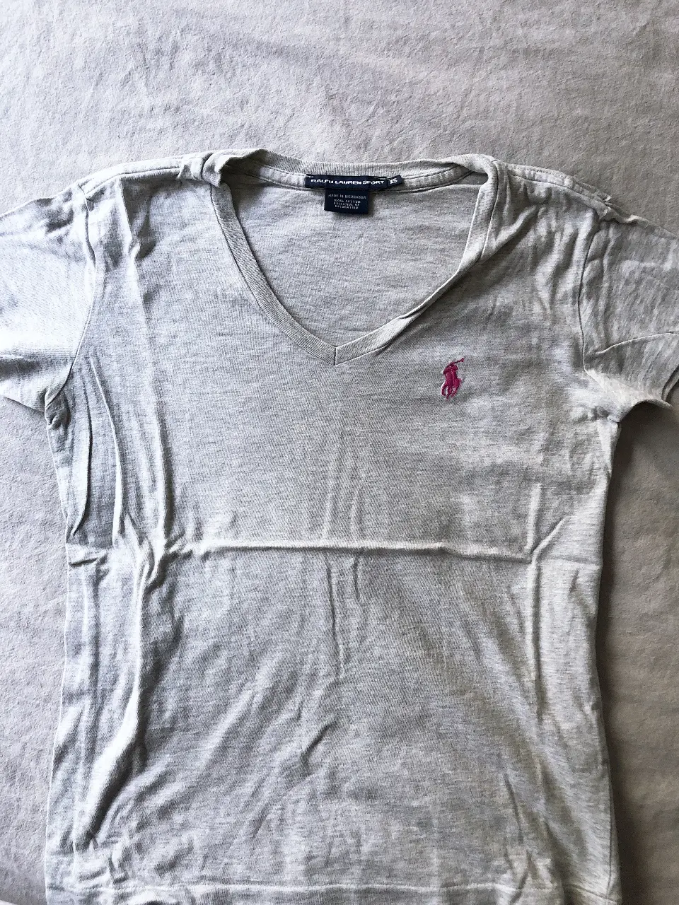 Remera de mujer Ralph Lauren Sport, color gris, con cuello en V y logo bordado en rosa. Talle XS. Ideal para un look casual y cómodo.