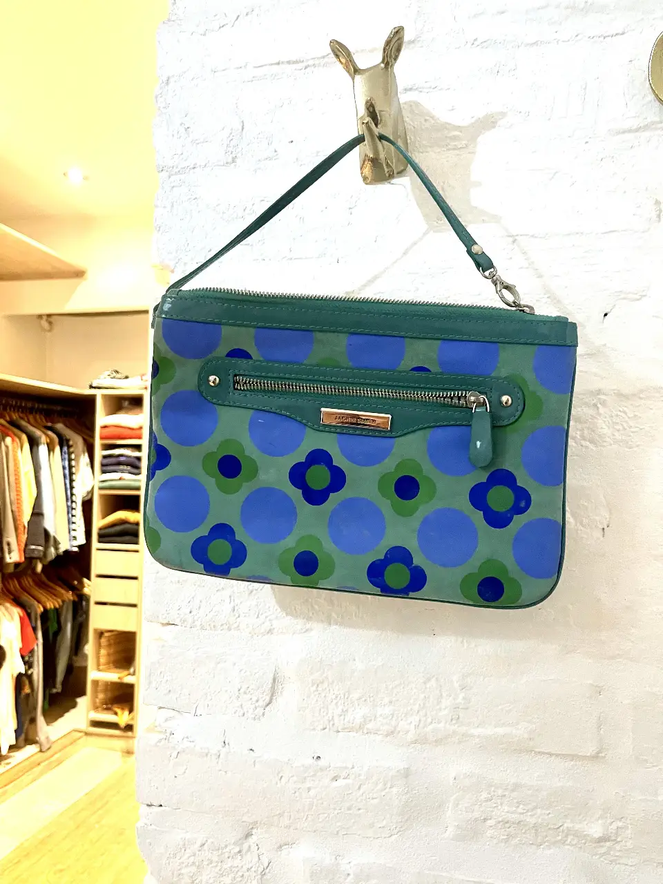 Cartera de mano Jackie Smith con estampado floral en tonos verde y azul. Detalles en verde oscuro y cierre con cremallera. Ideal para un look retro y con estilo.