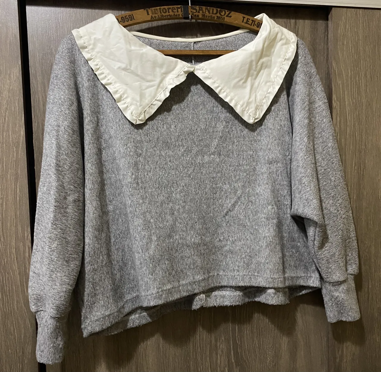 Sweater gris con cuello blanco de tela rígida y volados.