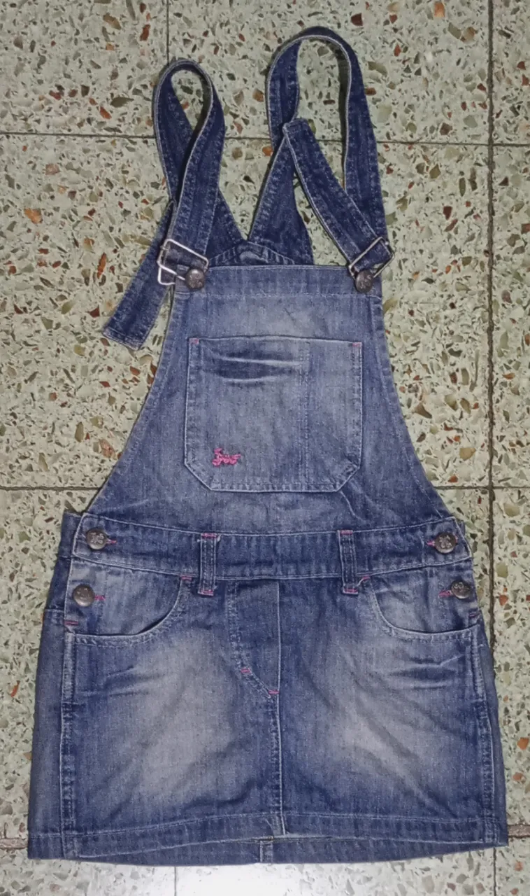 Enterito de jean corto, con tiradores regulables y detalles de costuras en rosa. Tiene bolsillos delanteros y traseros, y un bolsillo superior con tapa. Ideal para un look casual y canchero.