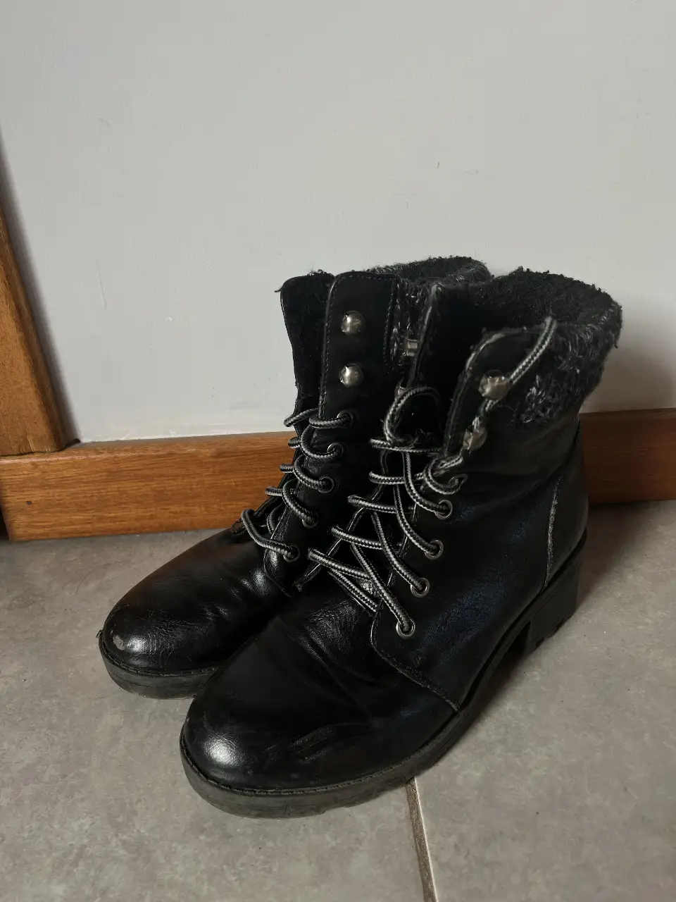 Borcegos negros de cuero sintético con cordones y detalle de peluche en el borde superior. Ideales para un look casual y abrigado en invierno.