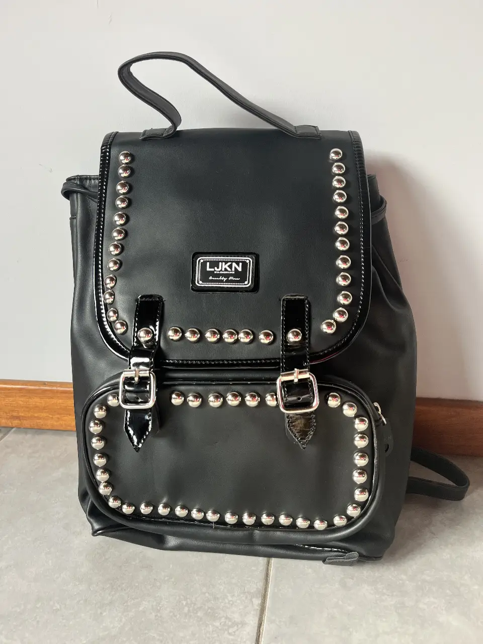 Mochila negra con tachas plateadas, ideal para un look canchero. Con hebillas metálicas, perfecta para llevar tus cosas con estilo.