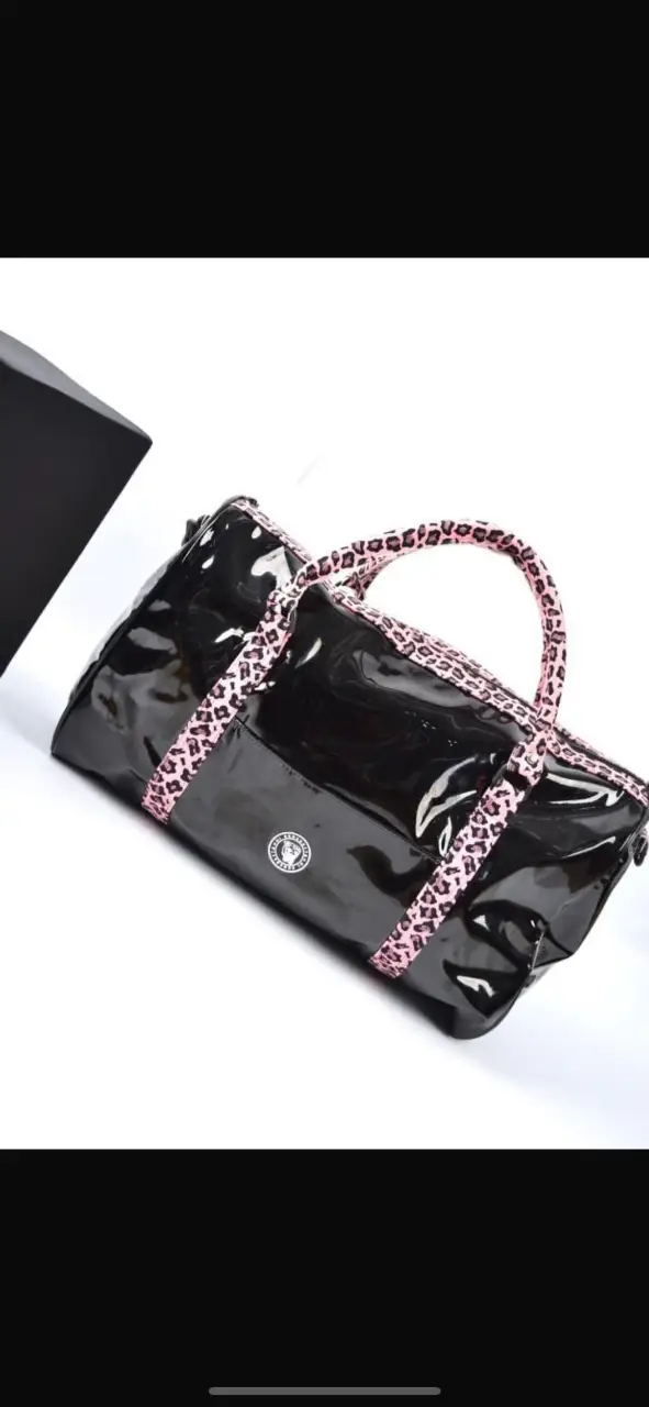 Bolso deportivo negro de charol con detalles en rosa y estampado de leopardo. Ideal para llevar al gimnasio o para viajes cortos. Diseño moderno y llamativo.
