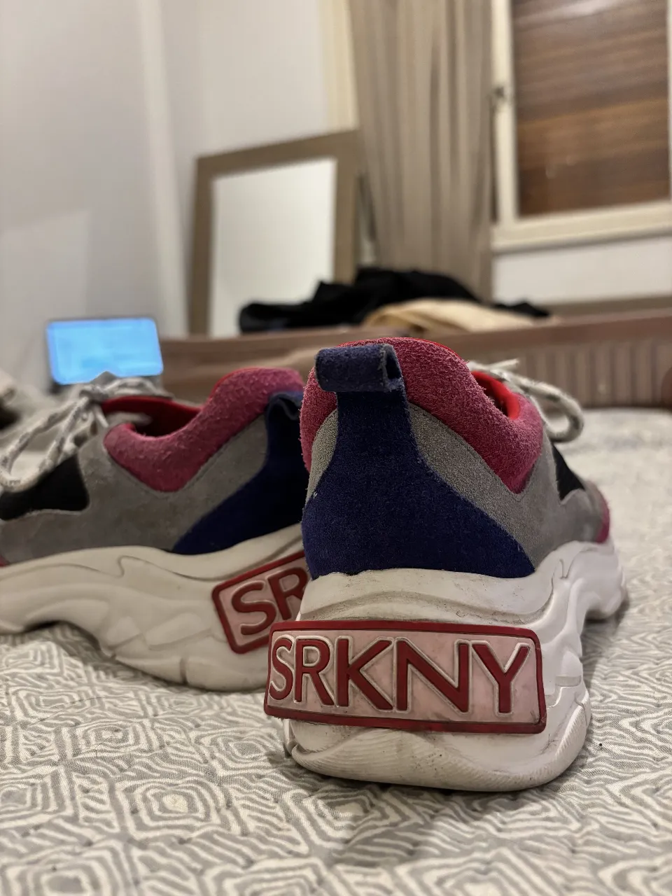 Zapatillas deportivas SRKNY para mujer, con detalles en gris, rosa y negro. Diseño chunky con suela gruesa y detalles de la marca. Ideales para un look urbano y moderno.