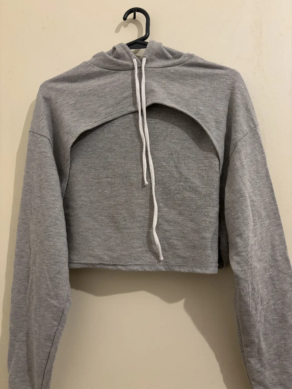 Buzo crop gris con abertura en el pecho. Ideal para un look casual y moderno.