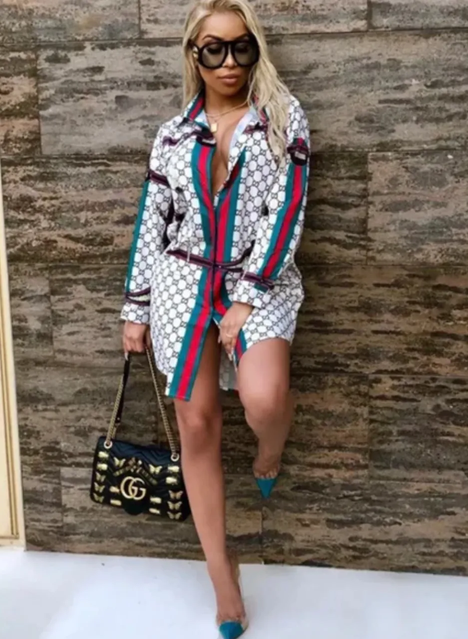 Camisa estampada con logo de marca, mangas largas y detalles de rayas verticales en rojo, verde y azul. Incluye un cinturón a juego. Ideal para un look canchero y a la moda.