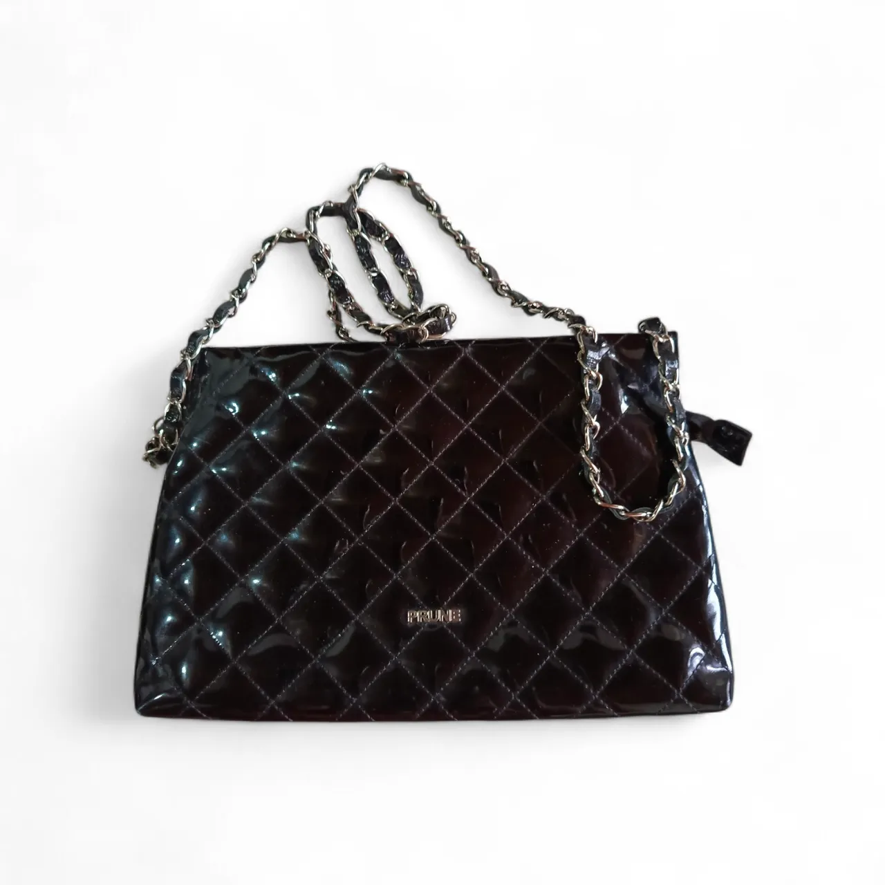 Bolso negro de charol con diseño acolchado y cadena metálica. Ideal para complementar looks de noche o eventos especiales.