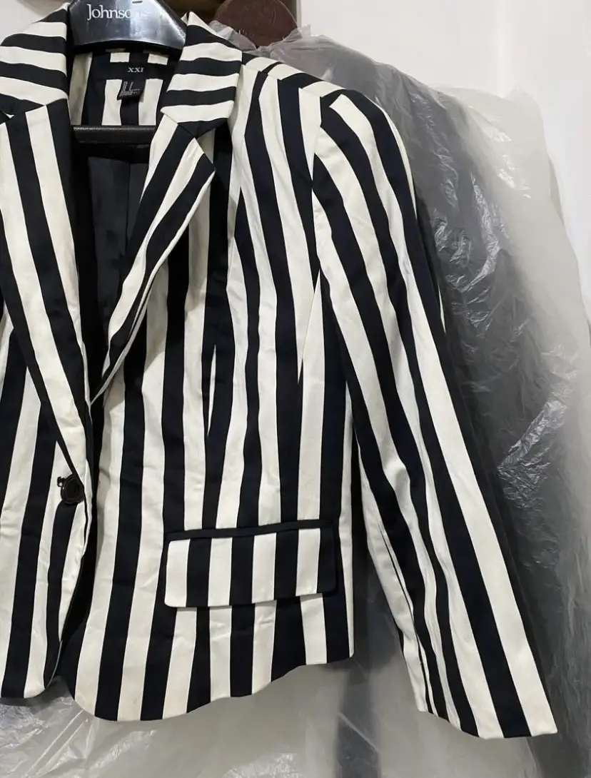Blazer a rayas verticales en blanco y negro, con corte clásico y solapas. Ideal para un look elegante y moderno.