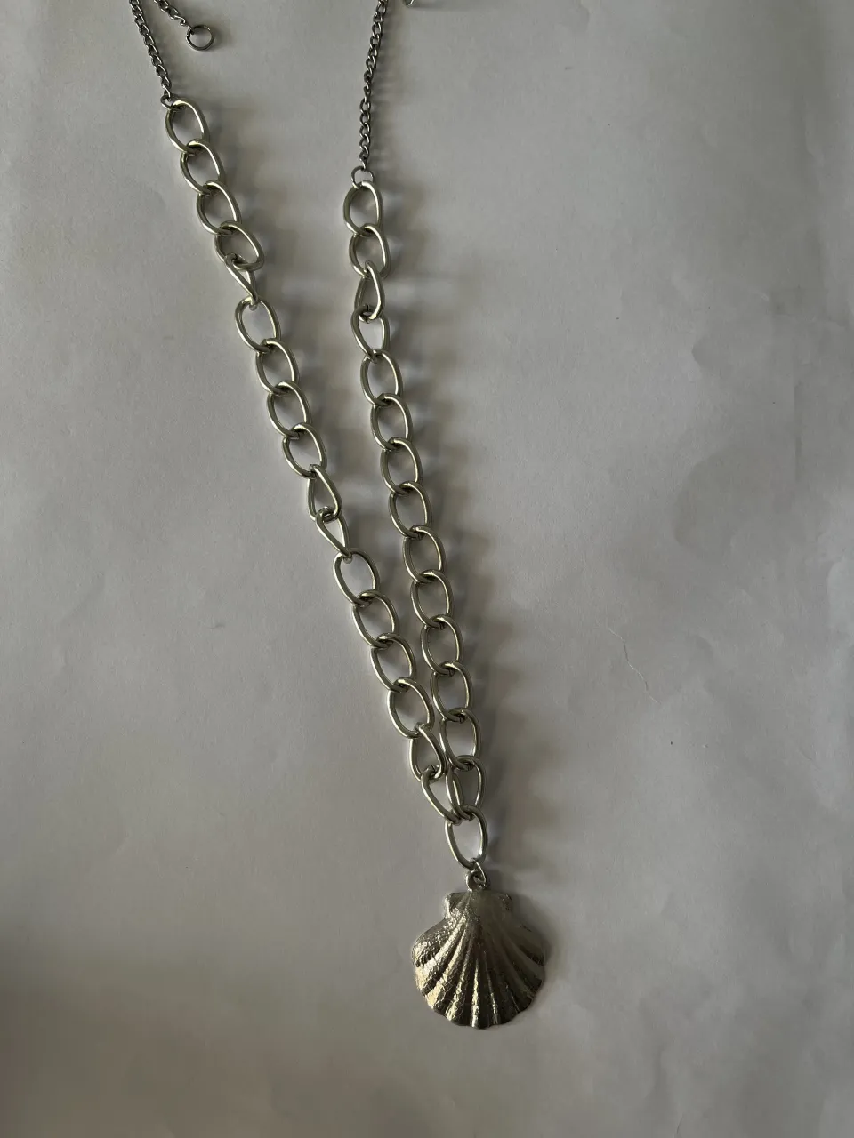 Cadena plateada con dije de concha marina.