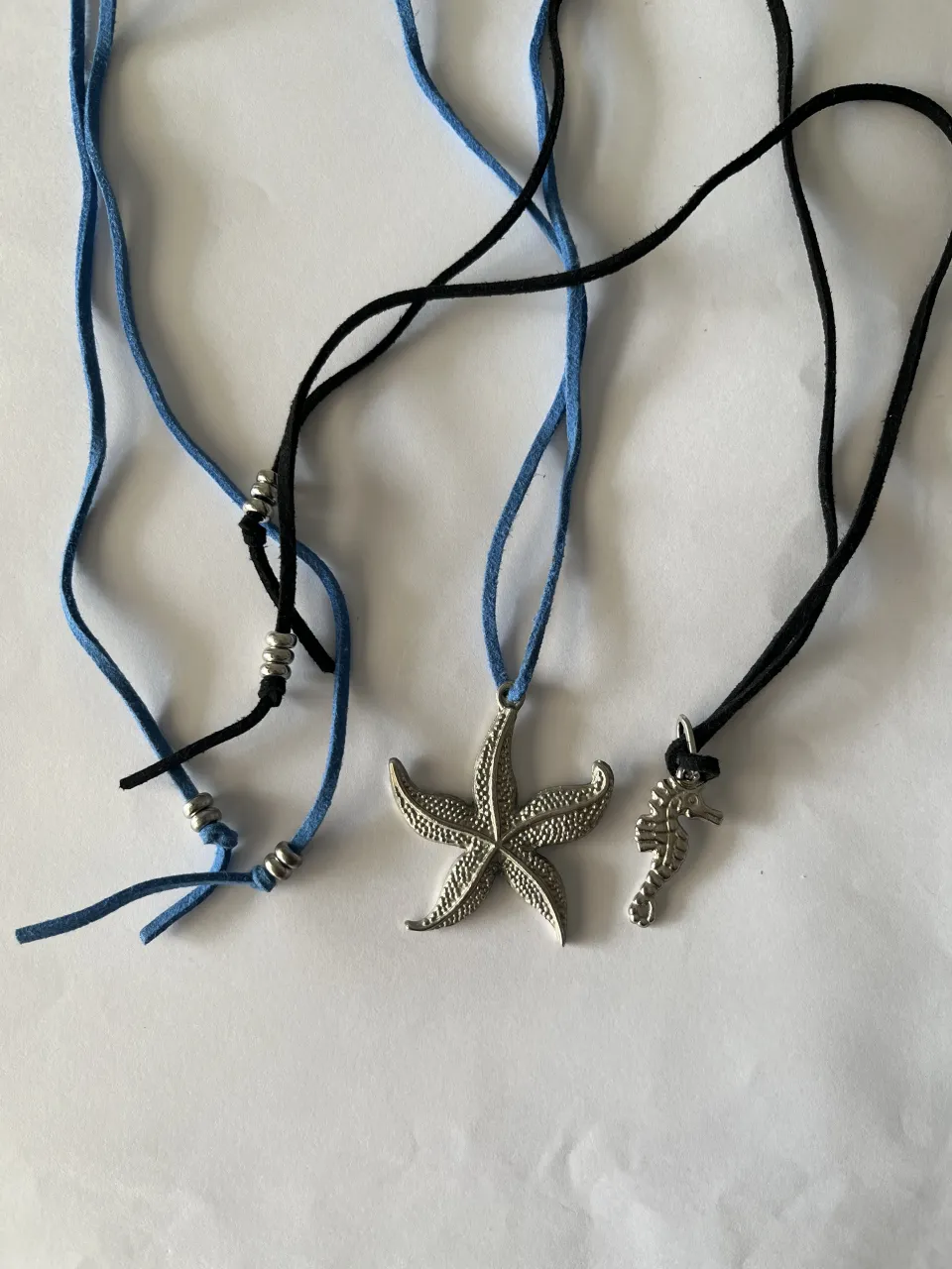 Collar con cordón azul y negro, con dije de estrella de mar y caballito de mar plateados.