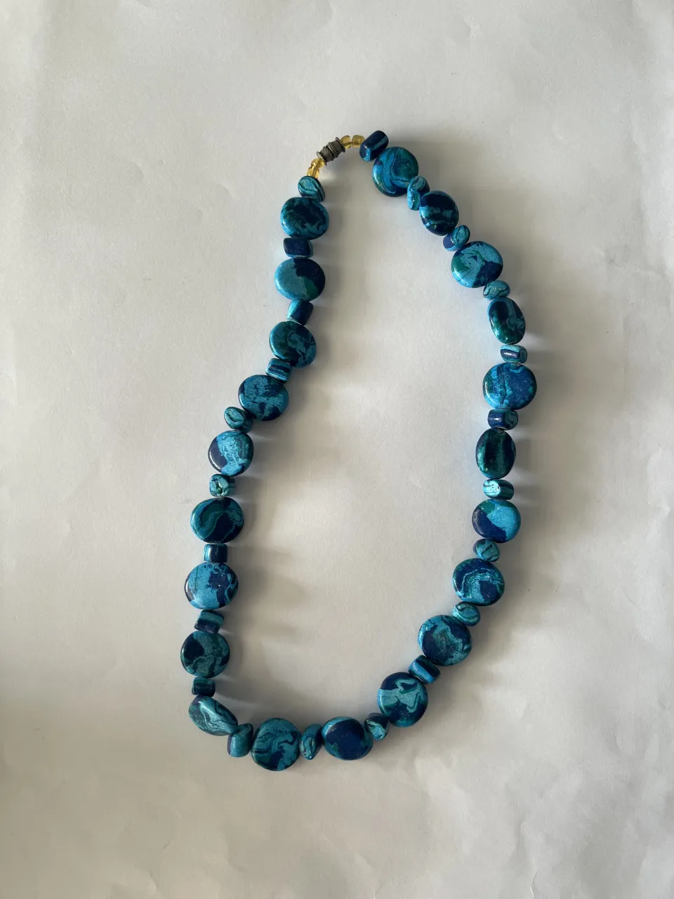 Collar de cuentas azules y verdes con cierre metálico.