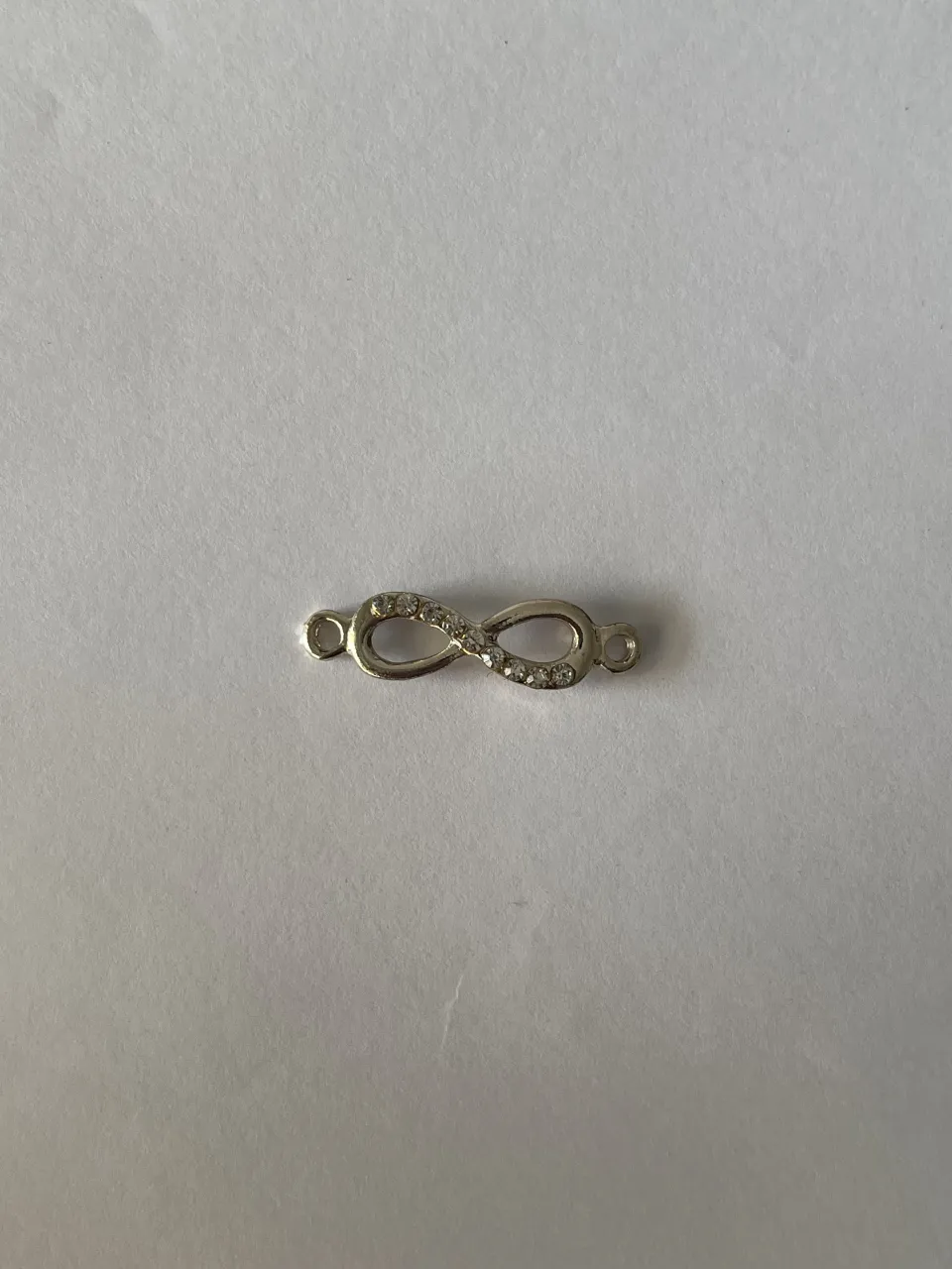 Dijecito con forma de infinito, con strass incrustados. Tiene dos argollitas para sujetar. ES DE PLATA❤️