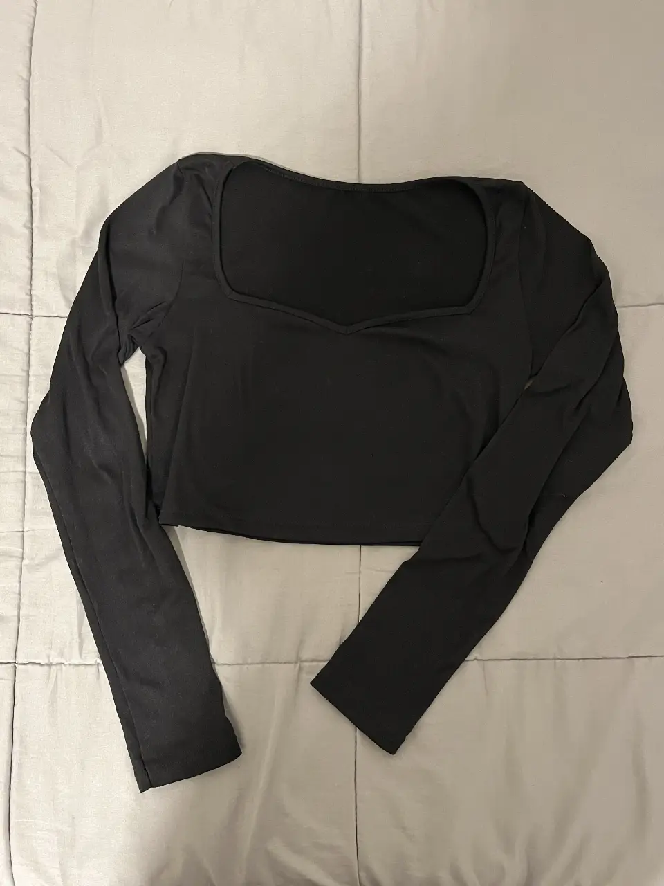 Top negro de manga larga con escote cuadrado, ideal para un look moderno y versátil. Perfecto para combinar con jeans o faldas.