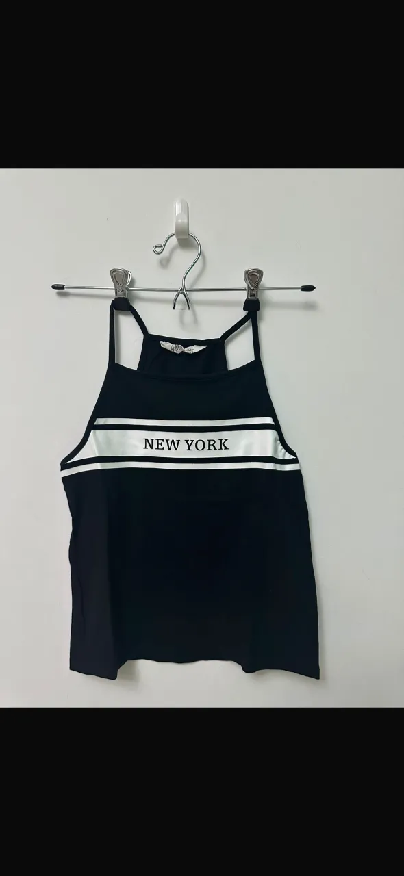 Musculosa negra con estampa "NEW YORK" en blanco y dos tiras blancas horizontales. Ideal para un look casual y urbano.