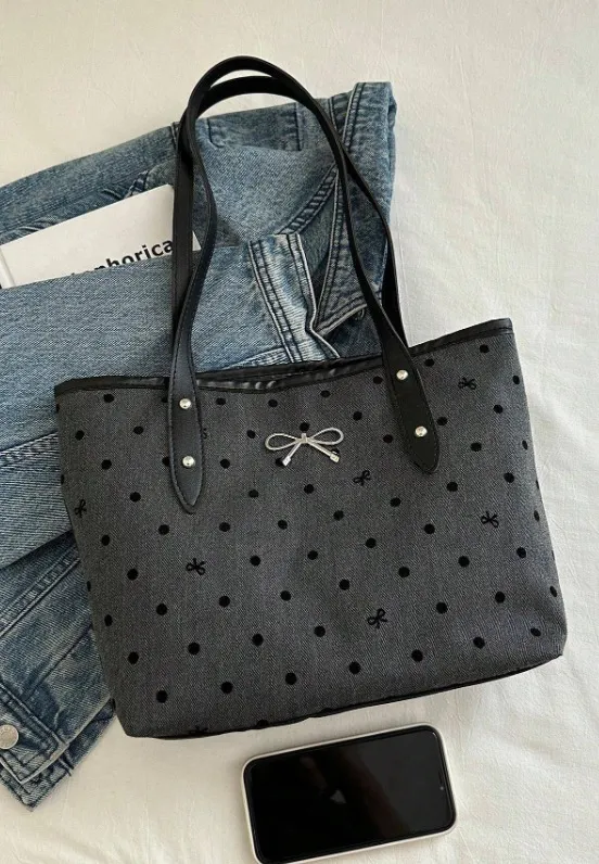 Bolso tote gris con estampado de lunares y moños. Ideal para llevar tus cosas con estilo. Perfecto para el día a día.