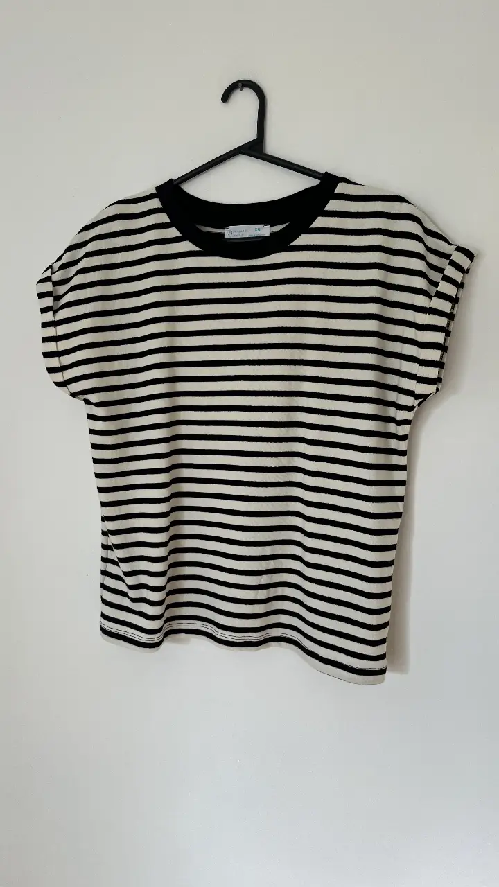 Remera a rayas horizontales en blanco y negro, con cuello redondo y mangas cortas con dobladillo. Ideal para un look casual y cómodo. Talle XS amplio. Va para M y L.