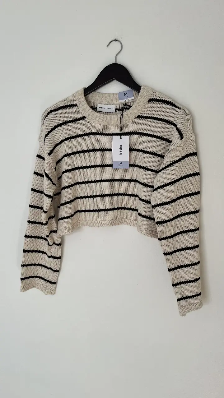 Sweater de mujer a rayas horizontales en color crudo y negro. Corte cropped, ideal para un look casual y moderno. Perfecto para combinar con jeans o pantalones de tiro alto.