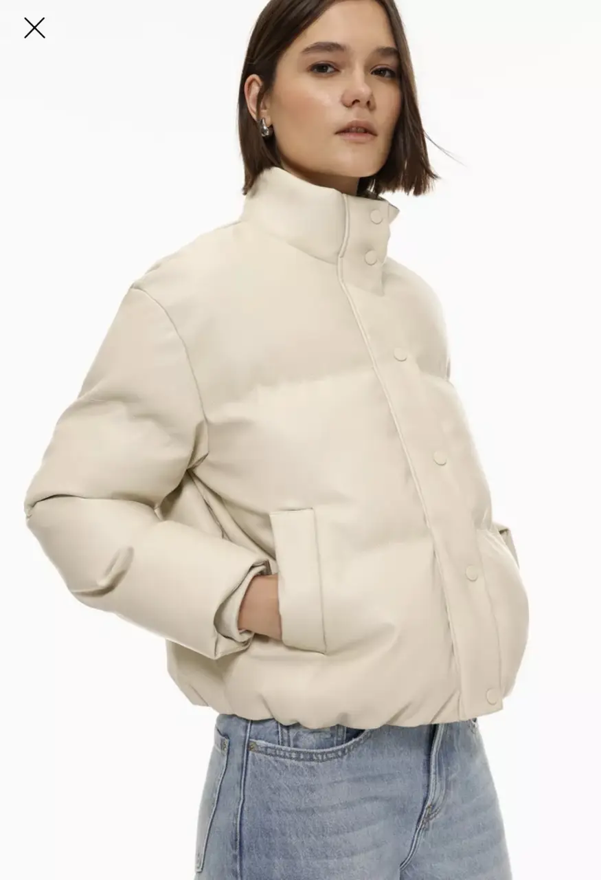 Campera bomber de cuero sintético color crudo, con cuello alto y cierre con botones. Ideal para un look casual y moderno.