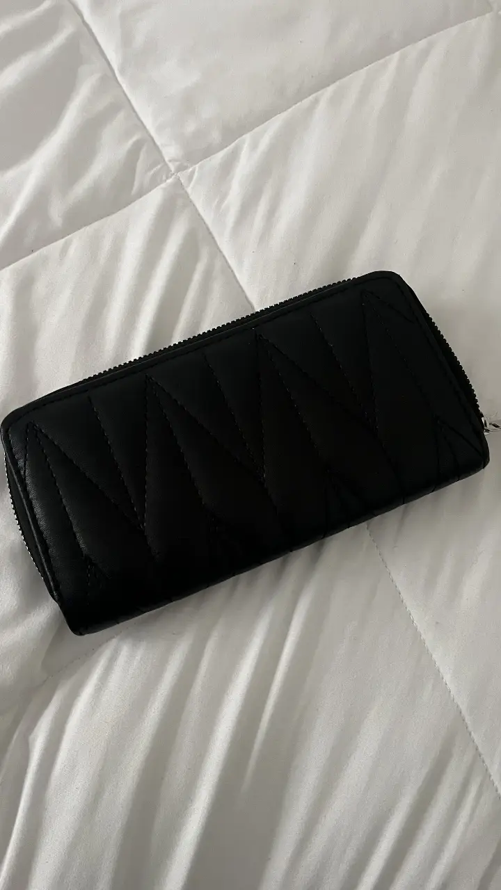 Billetera negra con diseño acolchado en forma de diamante. Cuenta con cierre y múltiples compartimentos internos para tarjetas y billetes. Ideal para organizar tus pertenencias con estilo.
