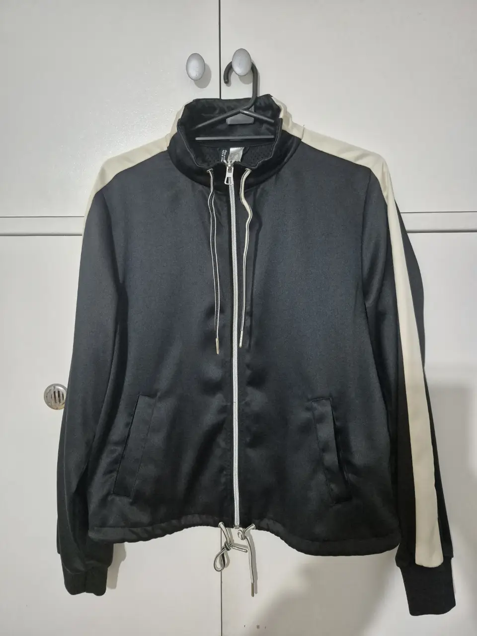 Campera deportiva negra H&M con detalles blancos/crema en las mangas. Ideal para un look casual y cómodo. Dos bolsillos. La prenda es más linda que como se ve en la foto. Medidas sisa a sisa: 49cm - Base/cintura: 51cm - de hombro a hombro: 39cm - largo de manga: 60cm - altura de base a hombro: 55cm.