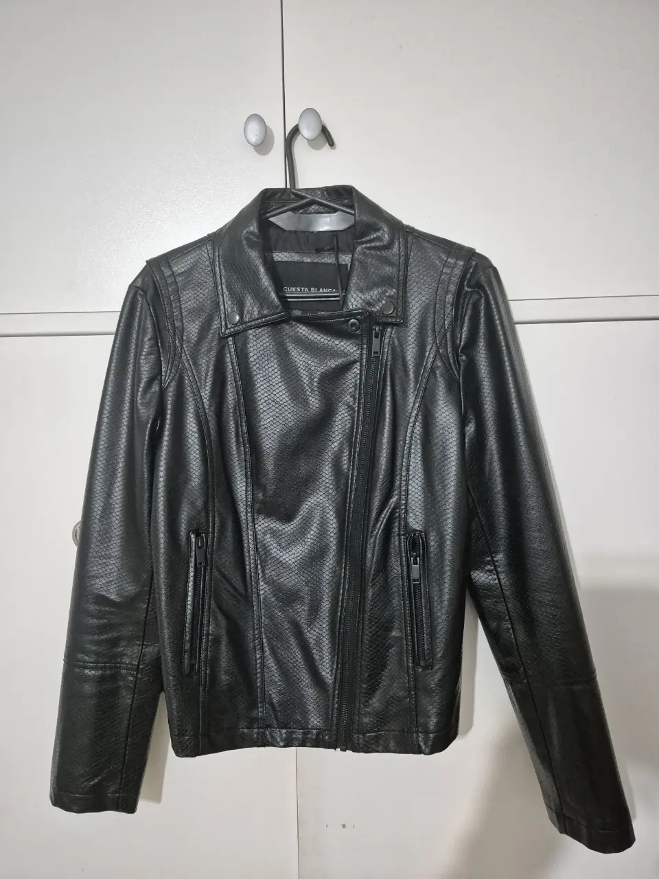 Campera de cuero sintético negra, tipo crocco, con detalles de costura y cierre asimétrico. Mangas con cierres. Ideal para un look rocker y casual. Talle 44. Medidas: - de sisa a sisa: 47cm - Cintura/Cadera: 44cm - Alto base a hombro: 57cm - Manga: 62cm de largo - Hombro a hombro: 41cm.