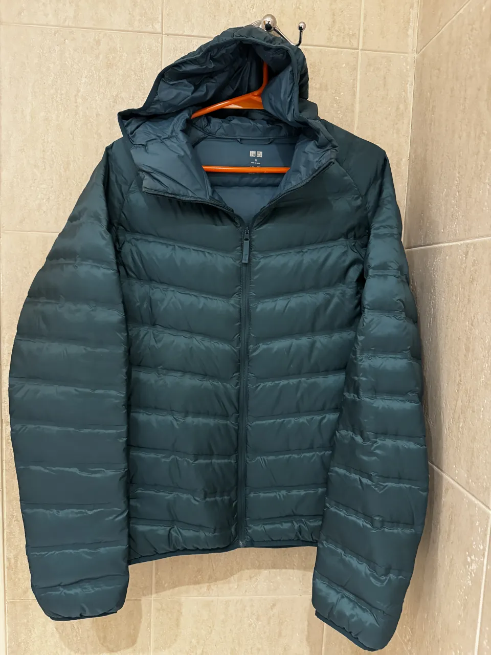 Campera acolchada verde con capucha y cierre al frente. Es liviana y viene con su bolsa para guardarla.