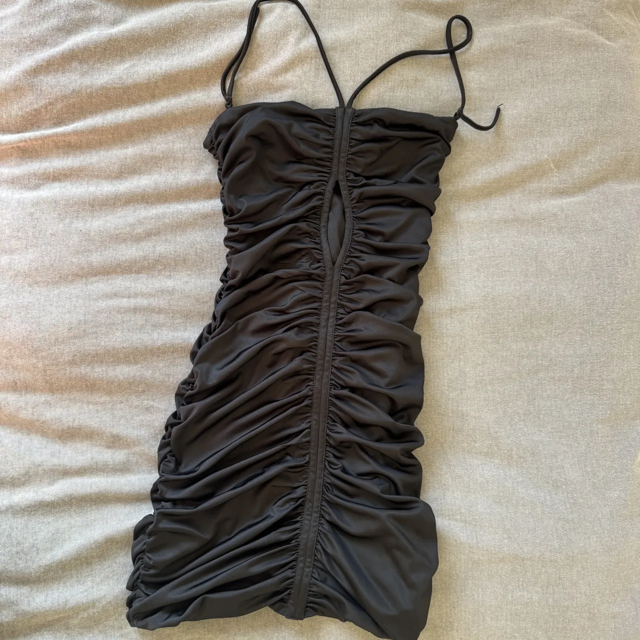 Vestido negro, con fruncido en toda la prenda y un corte al frente.