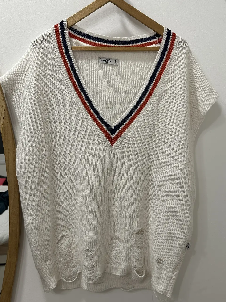 Chaleco de tejido de punto blanco con detalles en cuello y bajo. Diseño con roturas en la parte inferior. Ideal para un look casual y moderno.