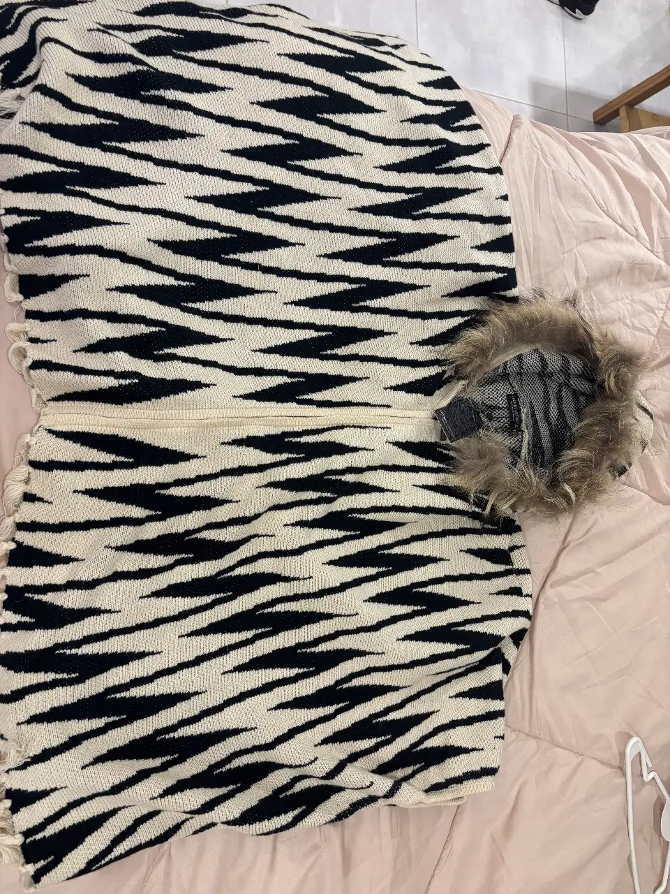 Sweater con capucha y detalles de piel sintética en el borde. Diseño con estampado de cebra en blanco y negro. Ideal para un look moderno y abrigado.