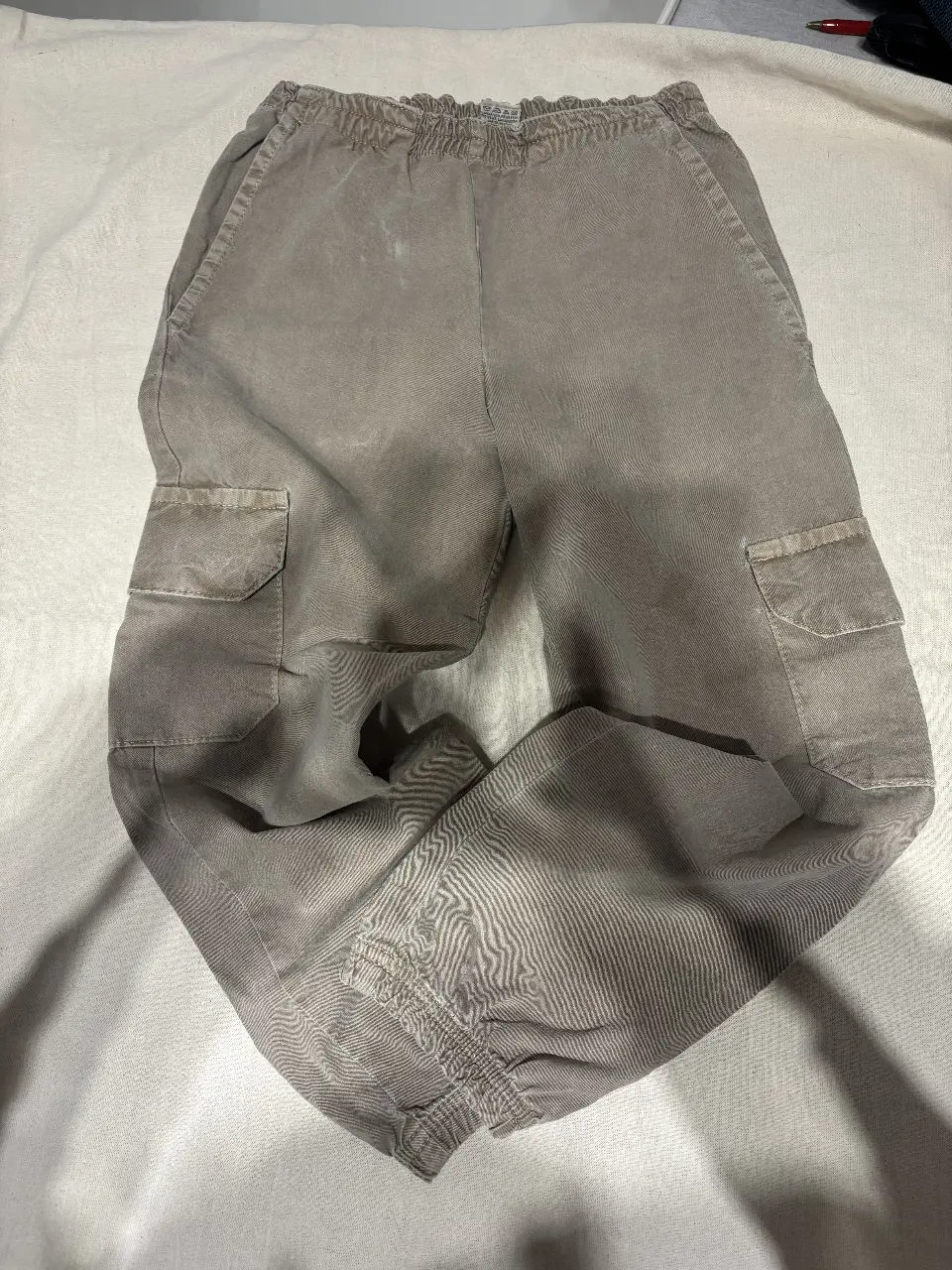 Pantalón cargo de hombre, color gris, con bolsillos laterales y ajuste en los tobillos. Ideal para un look casual y cómodo.