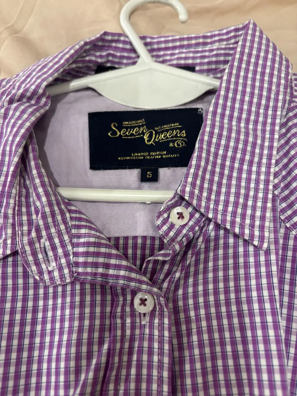 Camisa a cuadros en tonos violeta y blanco, con mangas largas y puños. Cuenta con dos bolsillos delanteros y un cuello clásico. Ideal para un look casual y versátil.
