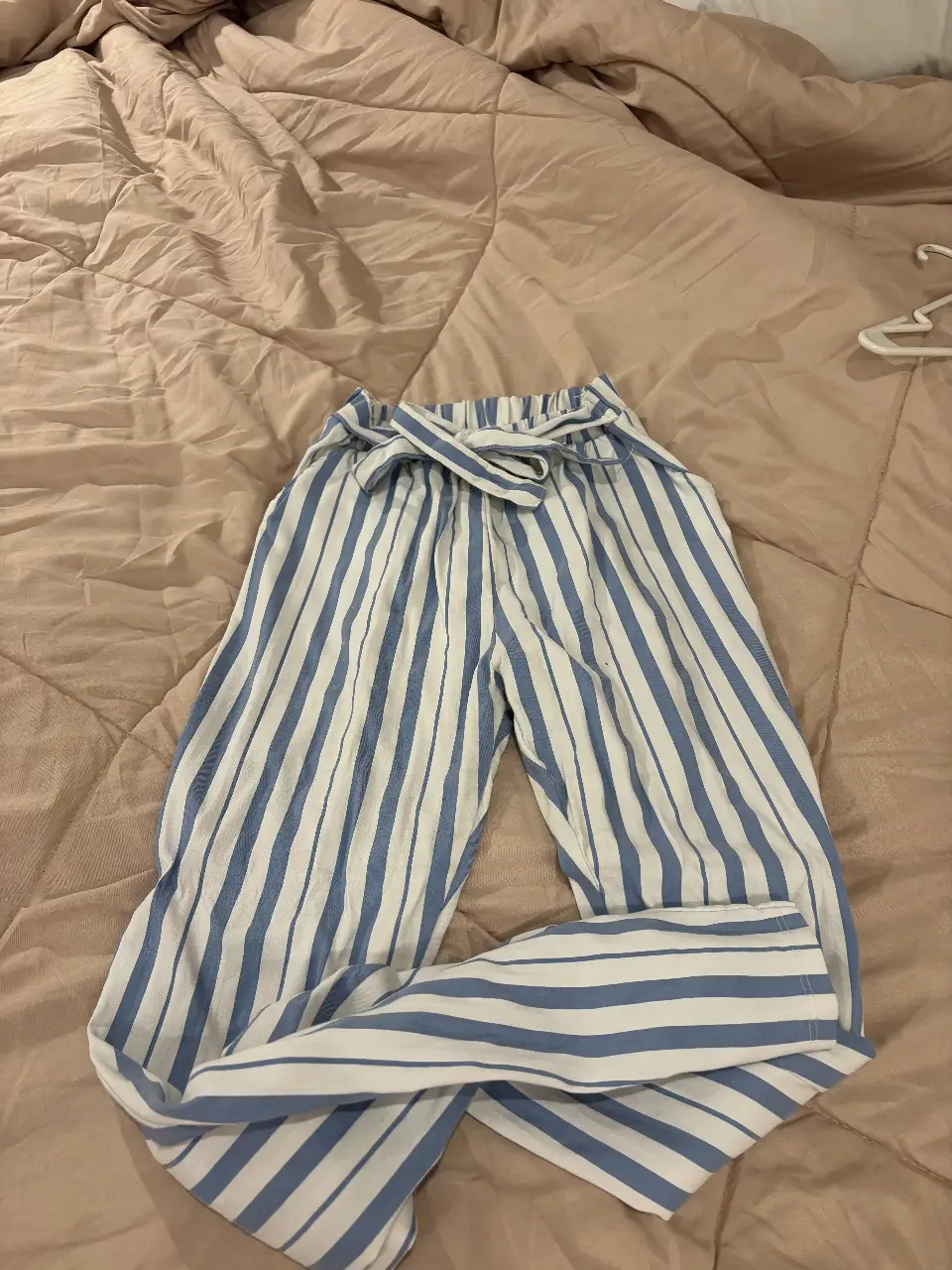 Pantalón suelto de mujer, a rayas verticales en blanco y azul. Con cintura elastizada y lazo para ajustar. Ideal para un look fresco y cómodo.
