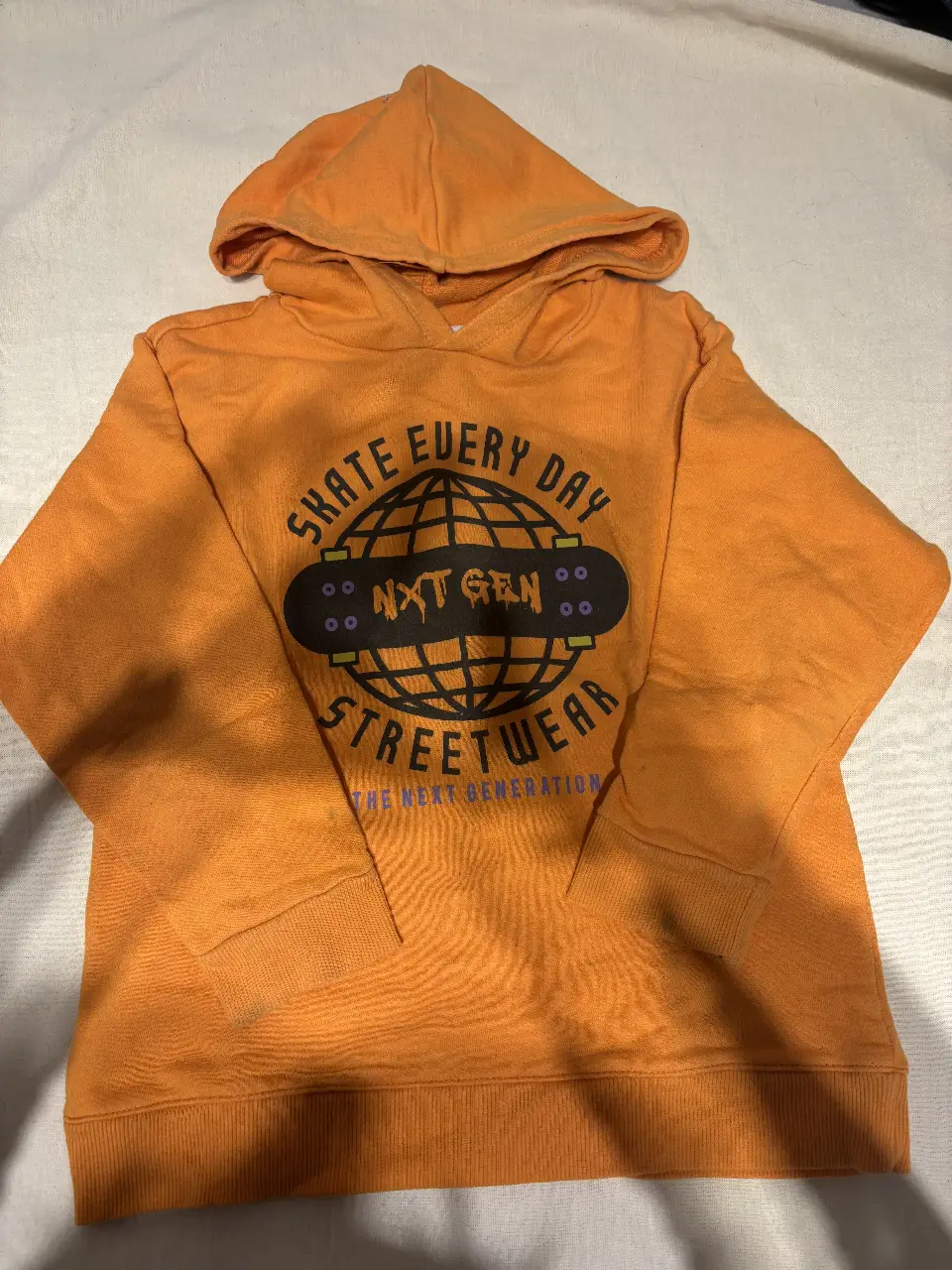 Buzo canguro naranja para niño con estampado de skate y la frase "Skate Every Day". Ideal para un look casual y urbano.