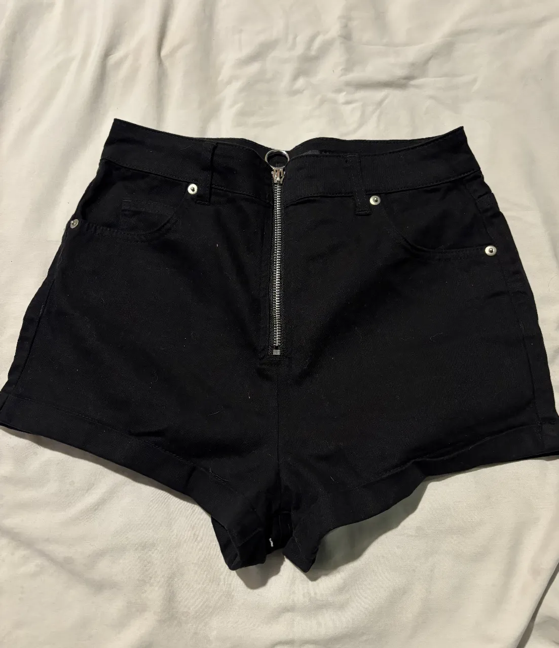 Short  negro de tiro alto con cierre frontal y bolsillos. Ideal para un look casual y moderno.