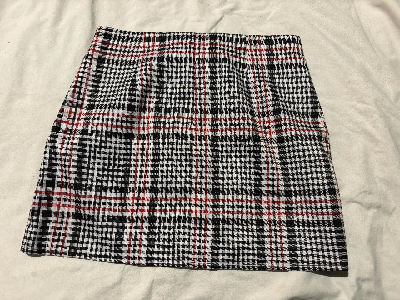 Minifalda de mujer con estampado a cuadros en blanco y negro con detalles en rojo. Cierre con cremallera frontal y talle M.