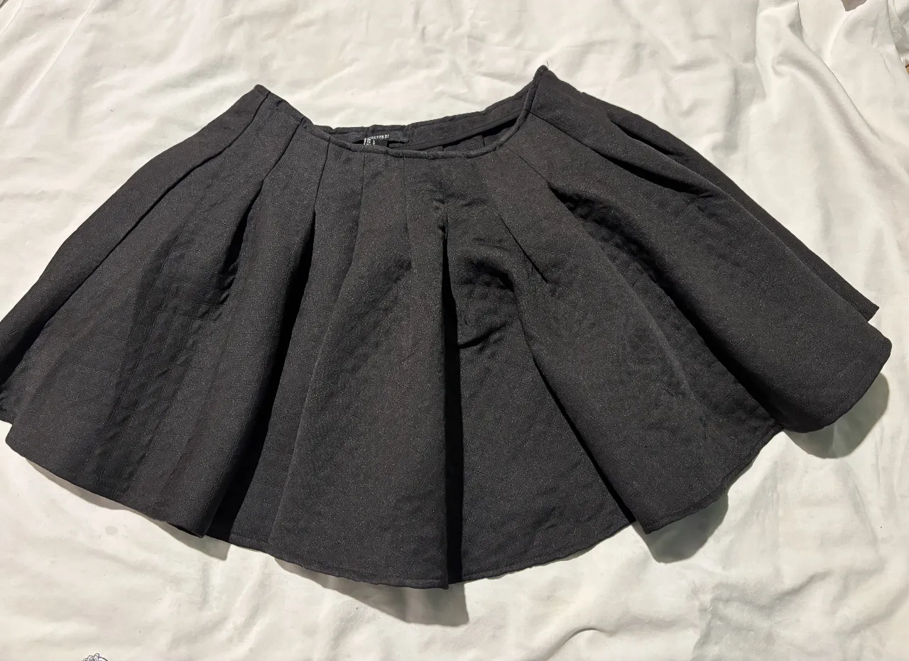 Minifalda negra con pliegues, ideal para un look elegante y versátil. Perfecta para combinar con diferentes tops y crear outfits modernos.