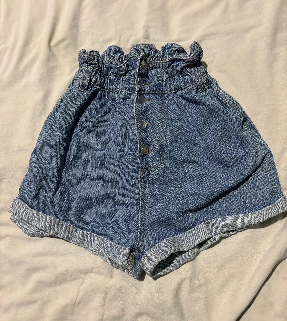 Short de jean tiro alto con cintura elastizada y botones. Ideal para un look casual y cómodo.