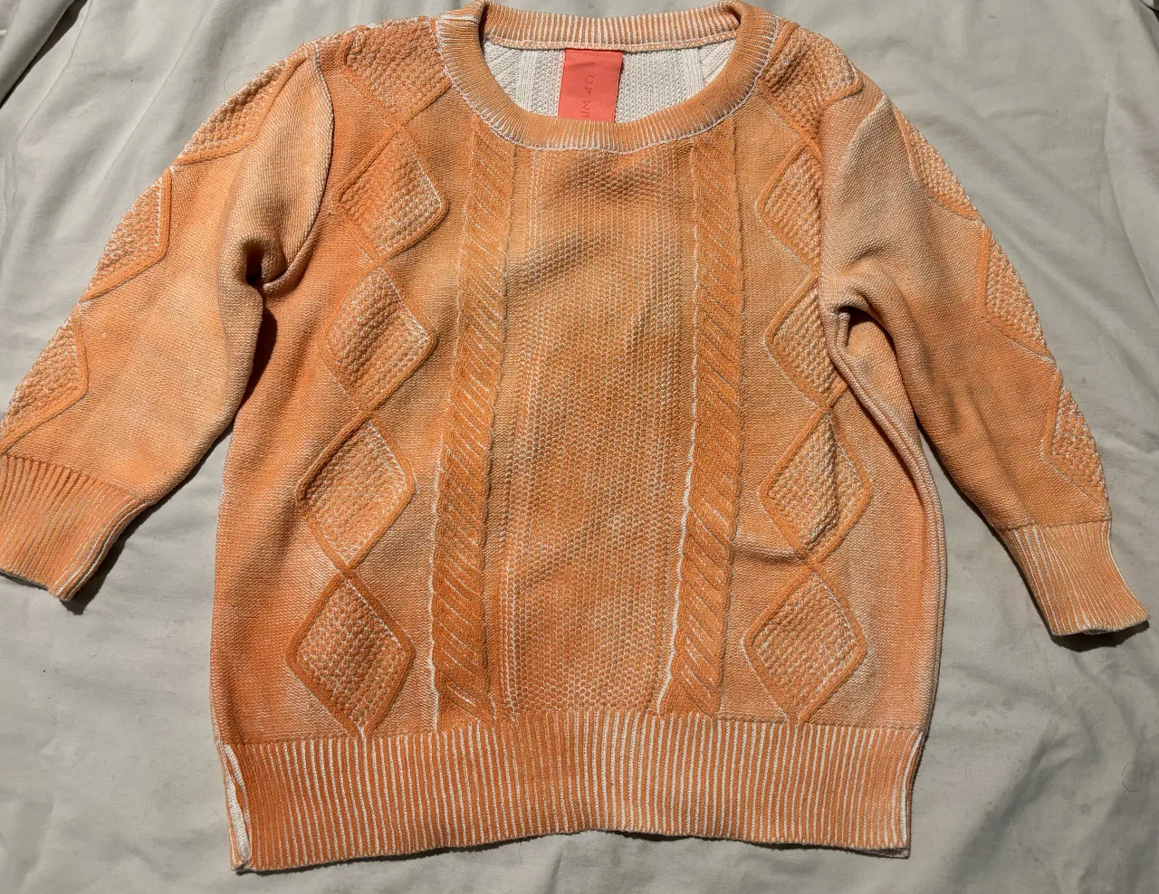 Sweater de punto en color naranja con detalles en blanco. Diseño con rombos en relieve y cuello redondo. Ideal para un look casual y abrigado.