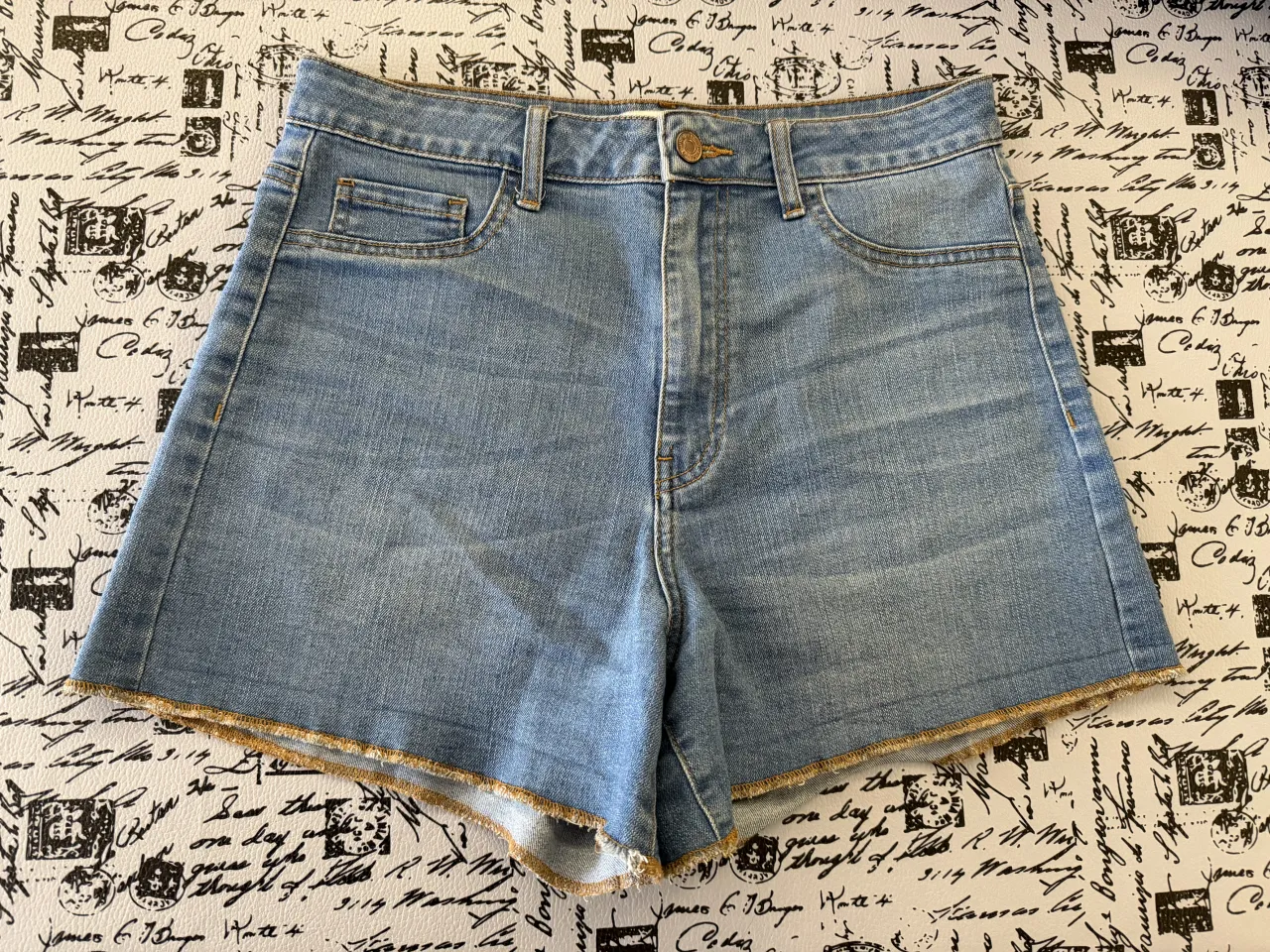 Shorts de jean tiro alto con costuras marrón claro. Posee bolsillos delanteros y traseros. Elastizado.