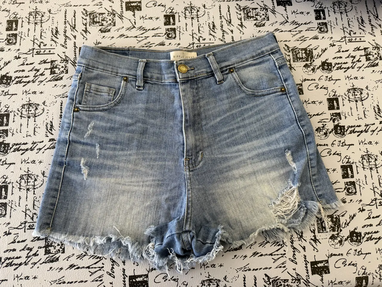 Shorts de jean tiro alto con roturas y detalles deshilachados en los bordes. Lavado celeste claro con desgastes. Elastizado.