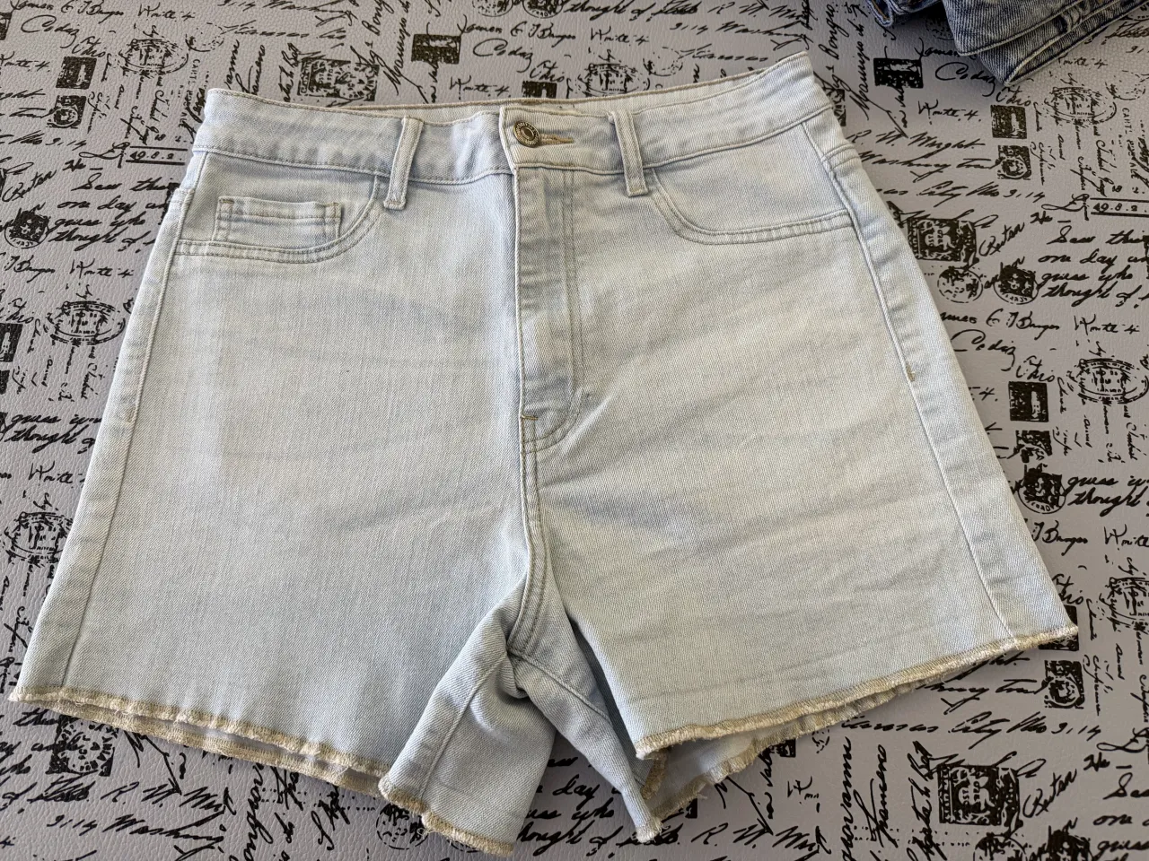 Shorts de jean tiro alto, color celeste claro, con costuras marrones. Elastizado.