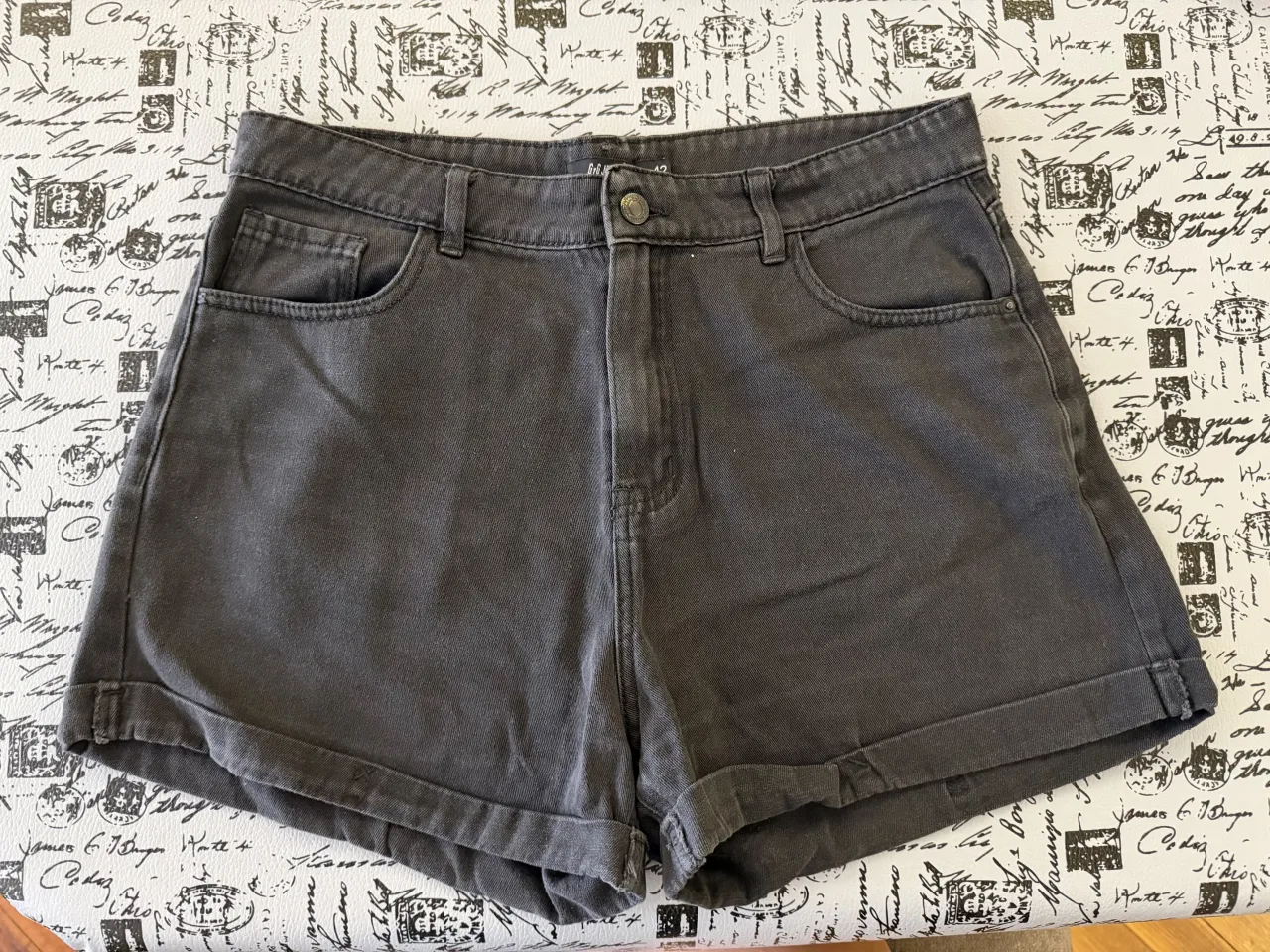 Shorts de jean color gris oscuro. Modelo con bolsillos, cierre y botón.