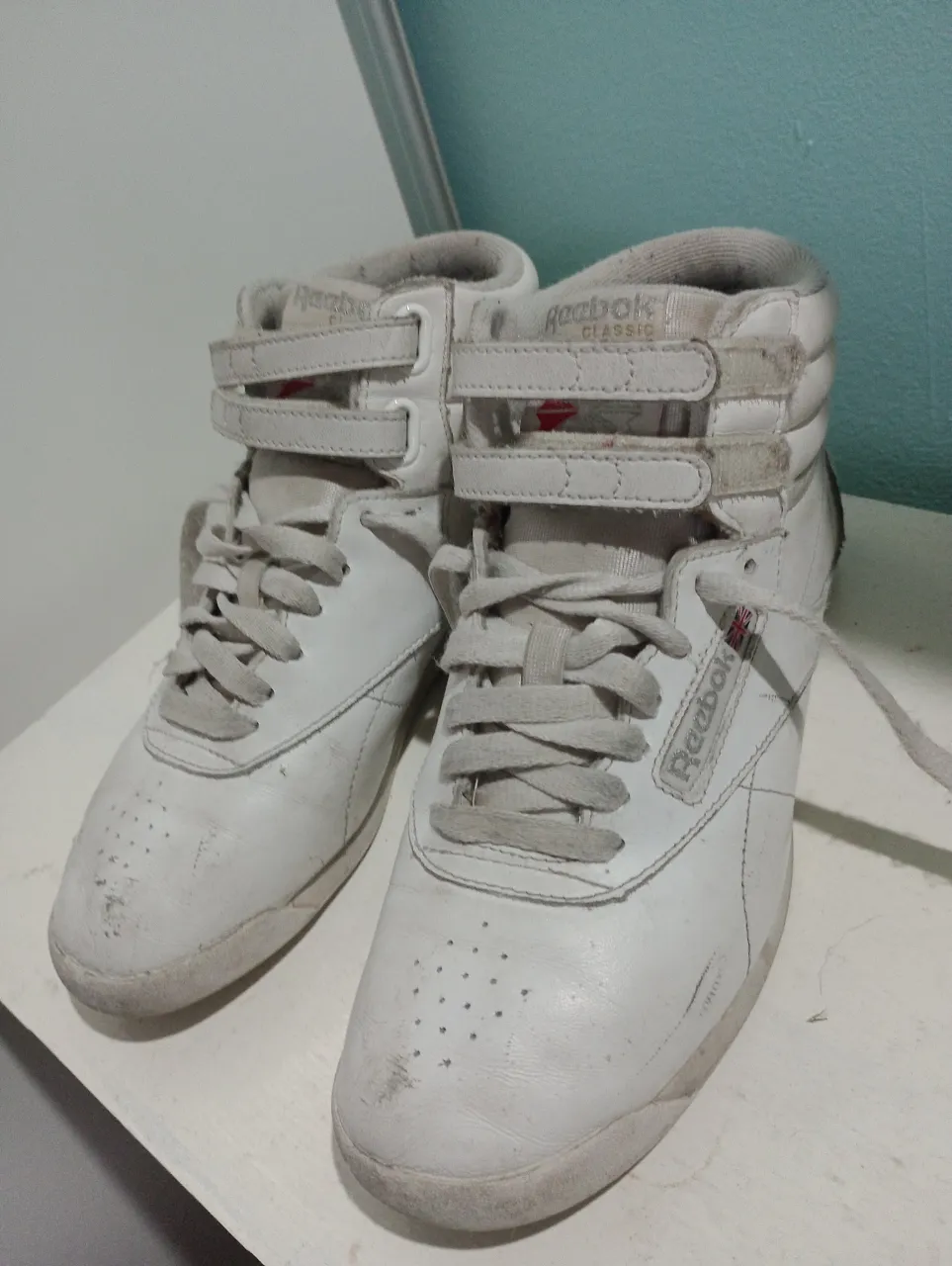Zapatillas Reebok Classic blancas de caña alta con cierre de velcro y cordones. Ideales para un look urbano y retro.