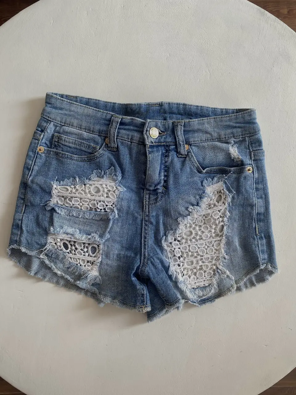 Short de jean de mujer, tiro medio, con detalles de encaje blanco en los laterales y roturas. spandex jean, estira bastante, Ideal para un look casual y fresco. 