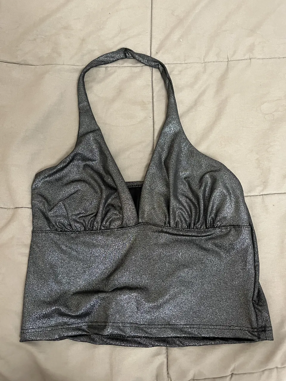 Top plateado con brillos, escote en V y tiras al cuello, estilo halter.  Ideal para salir o una fiesta. Tiene un solo uso