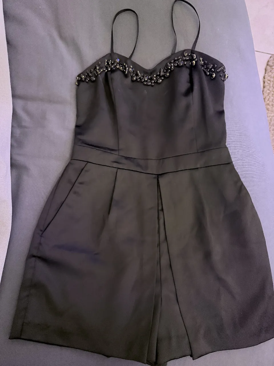 Mono negro corto con tiras finas y detalles de pedrería en el escote. Ideal para una salida nocturna o una fiesta.