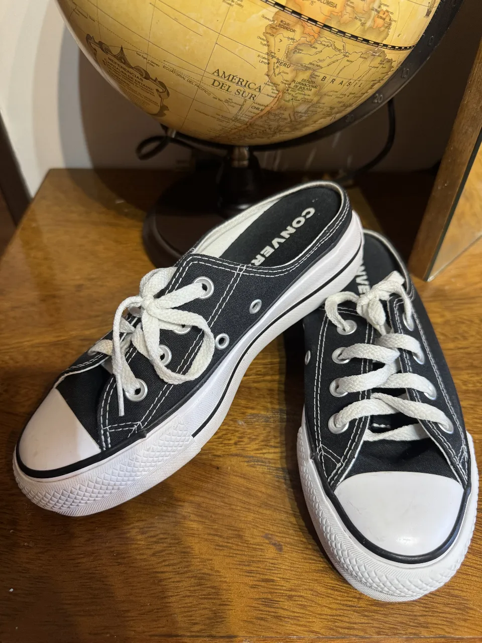 Zapatillas Converse estilo mule, negras con detalles blancos y cordones. Perfectas para un look casual y cómodo.