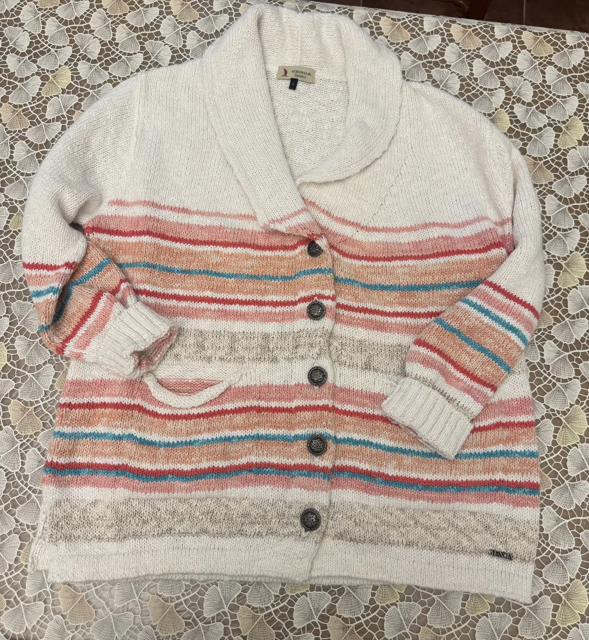 Cardigan de lana tejido a rayas horizontales en tonos pastel. Tiene botones y bolsillos.